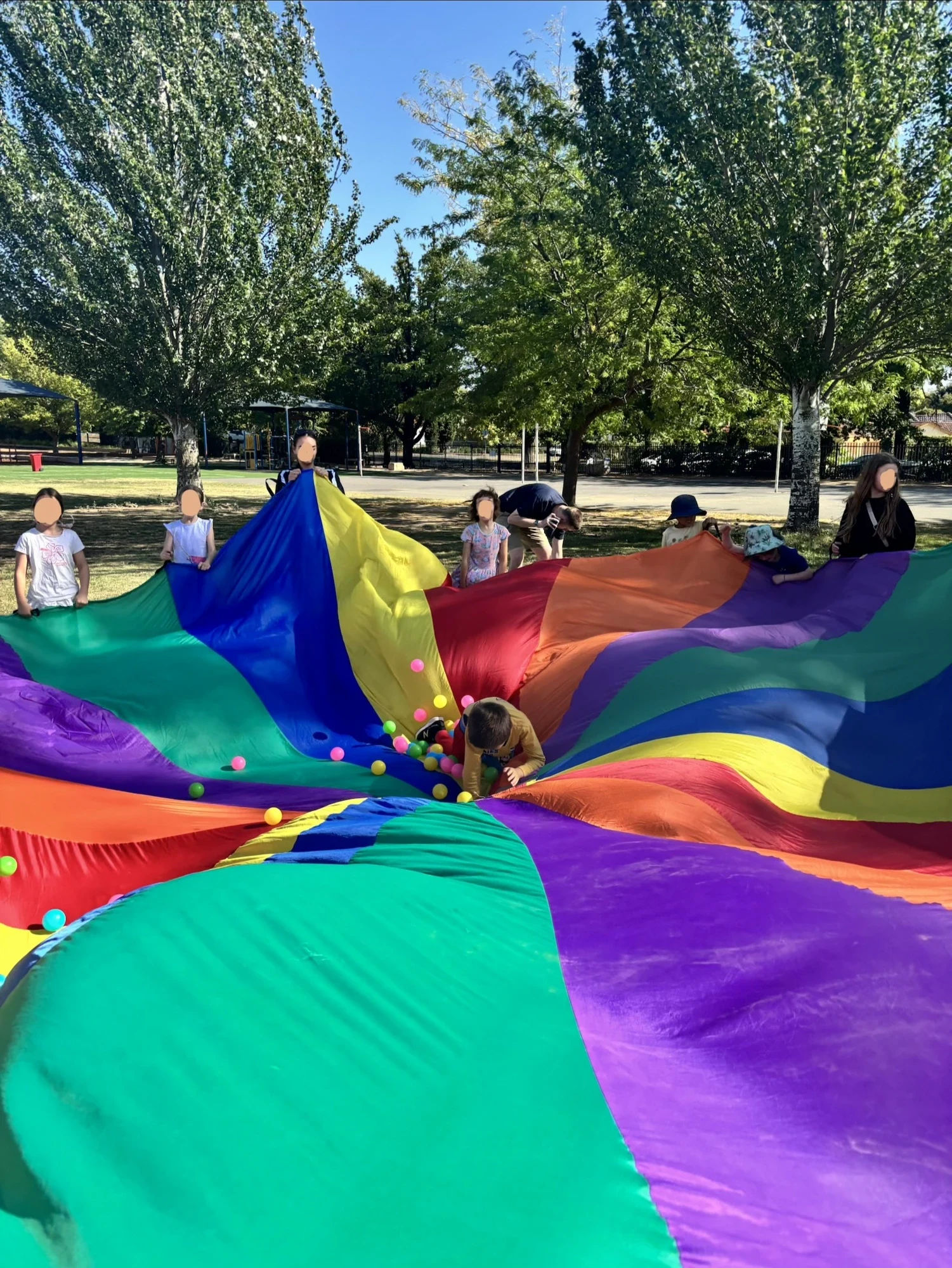 Children playing a parachute game together on the school grounds