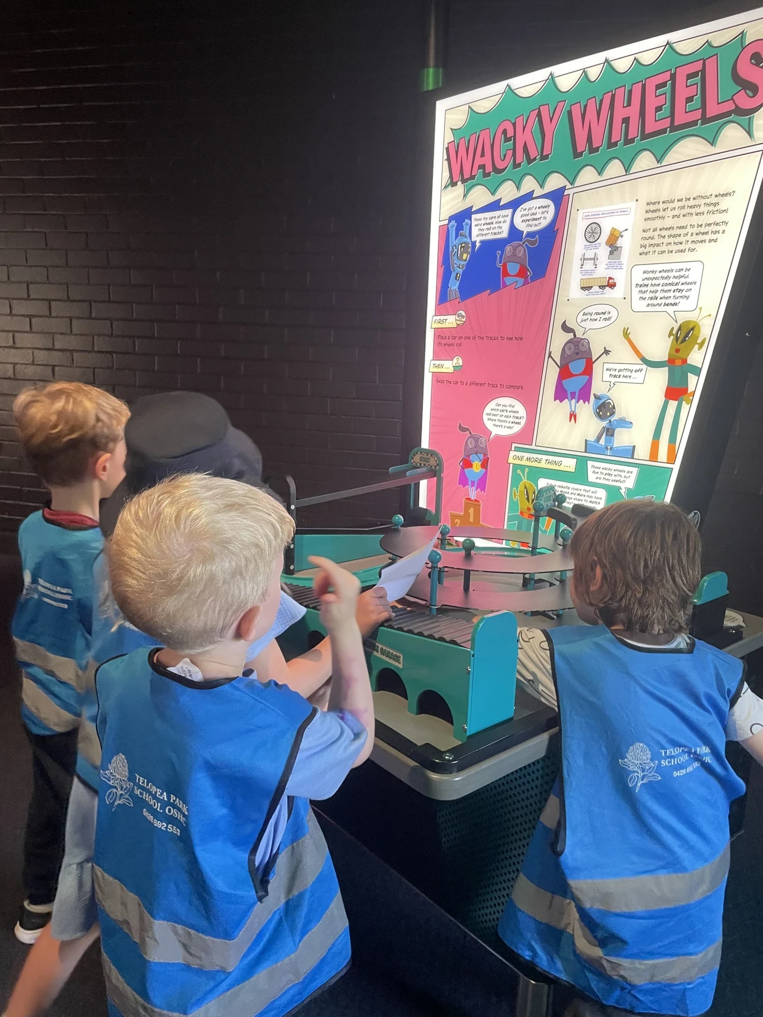 Children in Telopea Park OSHC hi-vis vests exploring an exhibit on an excursion